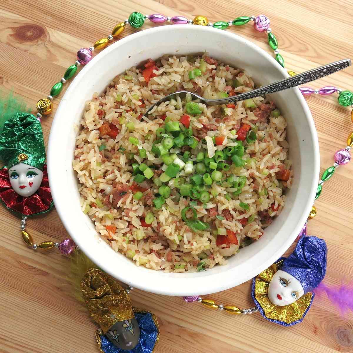 Easy Cajun Dirty Rice with Sausage in bowl surrounded by Mardi Gras beads.