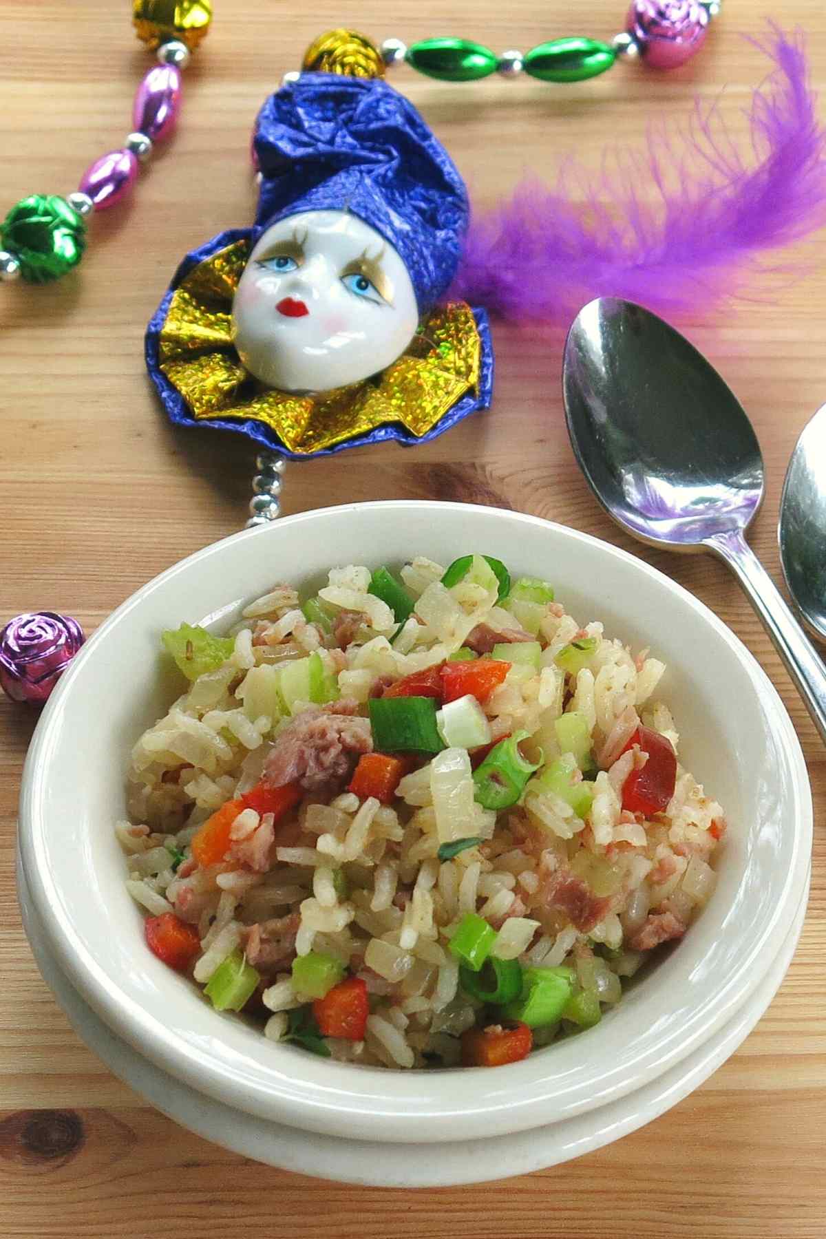 Side dish of recipe with spoons and Mardi Gras beads in the background.