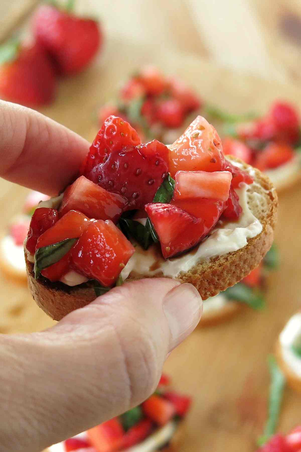Fingers holding low-carb strawberry appetizer.