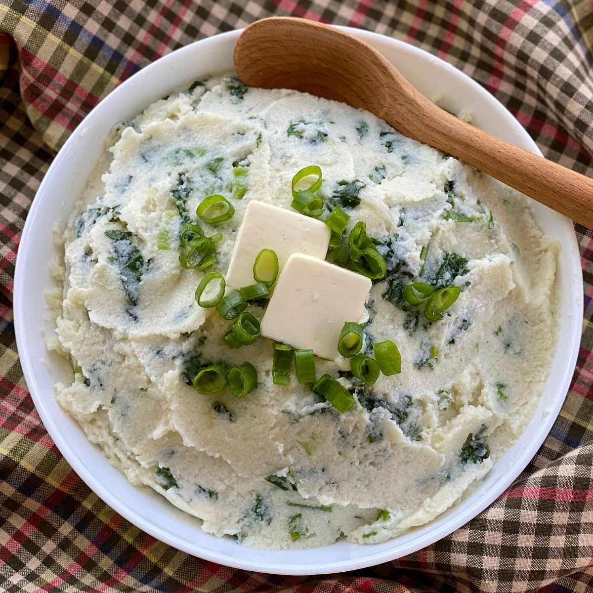 Bowl of cauliflower colcannon with a wooden spoon.