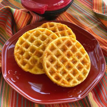 Keto chaffles on plate with Dash mini waffle maker behind it.
