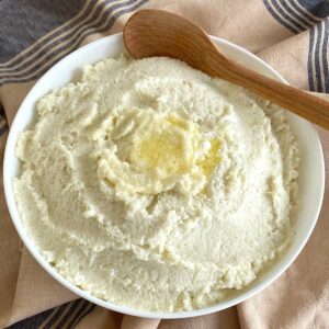 Frozen cauliflower mash in serving bowl with wooden spoon.