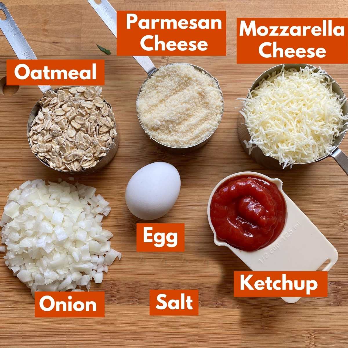 Labeled ingredients to add to ground chicken to make chicken meatloaf: oatmeal, Parmesan cheese, mozzarella cheese, diced onion, egg, ketchup, and salt.