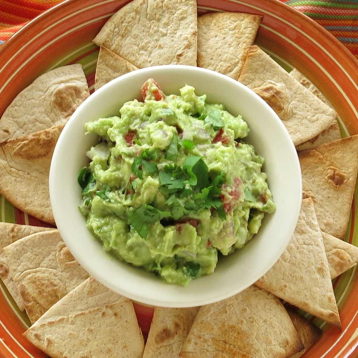 Guacamole in a bowl surrounded by homemade low-carb flour tortilla chips.