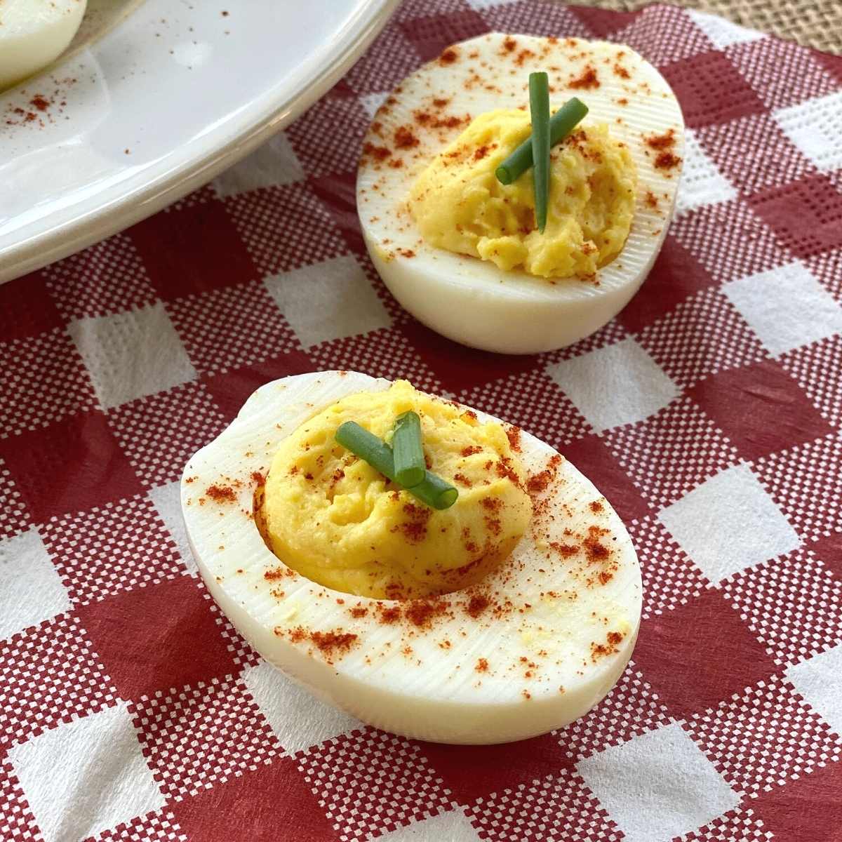 Two halves of low-carb deviled eggs on a red and white checkered napkin.