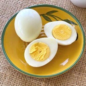 2 hard boiled eggs cooked in a Ninja Air Fryer. 1 is whole, the other cut in half.