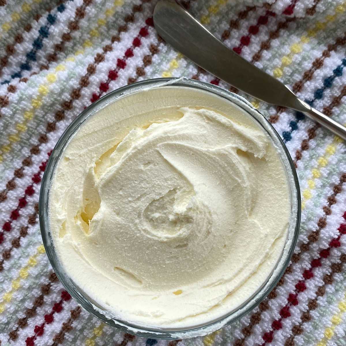 Bowl of previously frozen cream cheese that has been stirred until creamy.