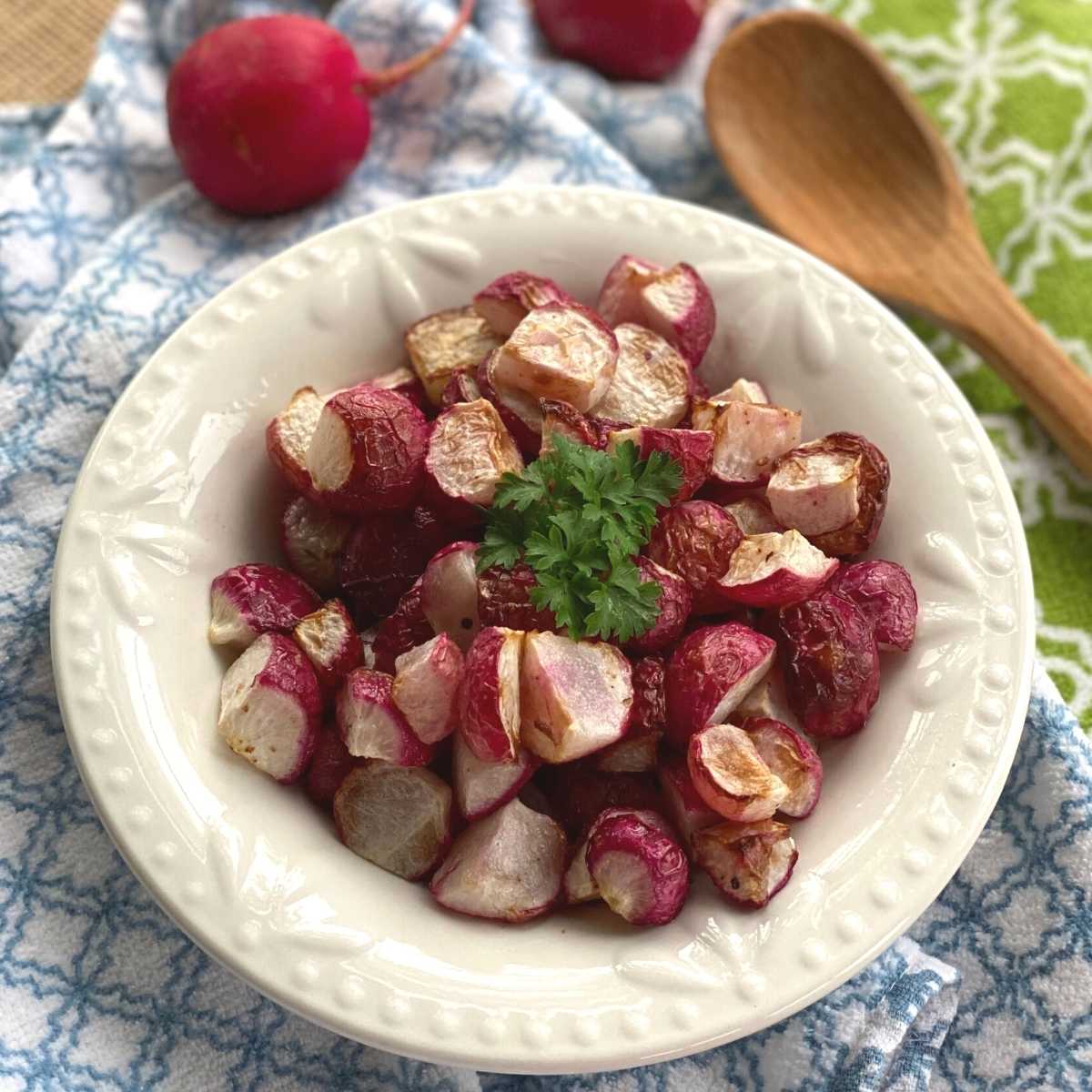 Air fried radishes in a bowl with wooden spoon next to it.