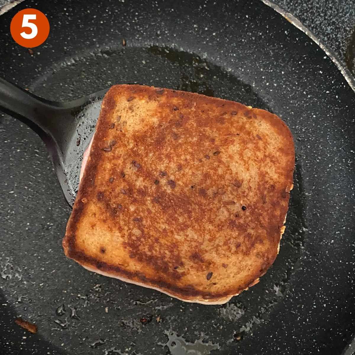 Step 5 Cooked grilled cheese on spatula in pan.