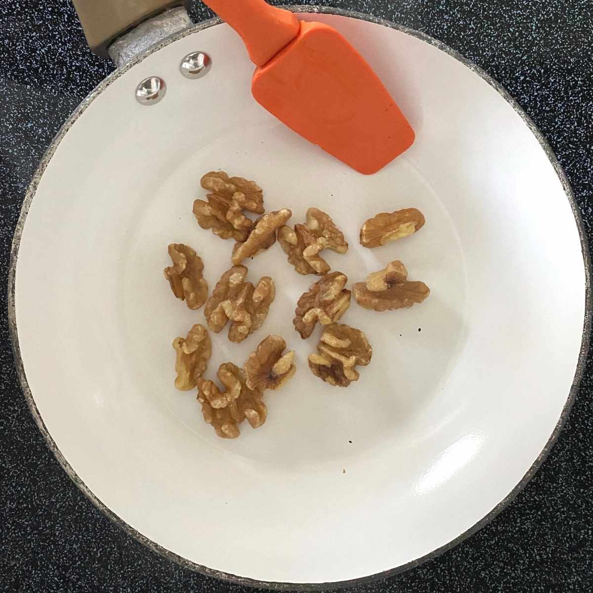 Walnuts in small skillet with spatula.