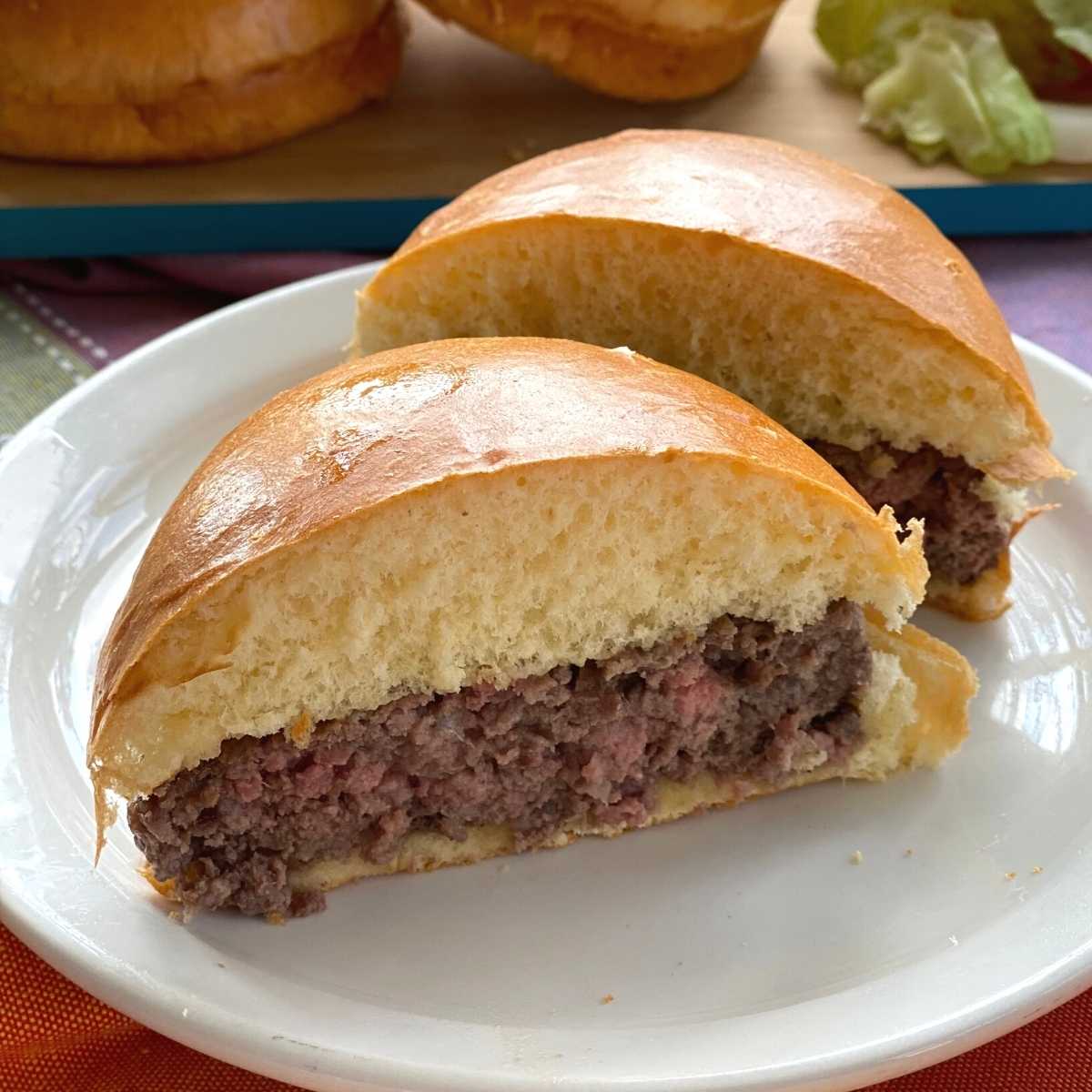 Cooked American Wagyu Beef Burger on bun cut in half.