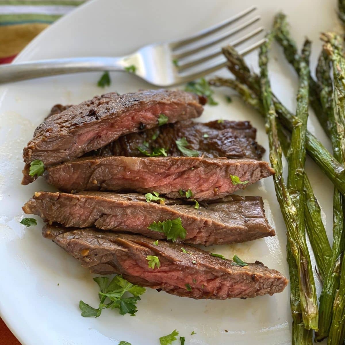 Cooked bavette steak on plate with asparagus and fork.