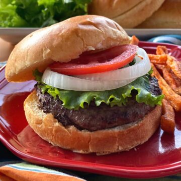 Wagu Beef Burger on a brioche bun topped with lettuce, onion, and tomato.