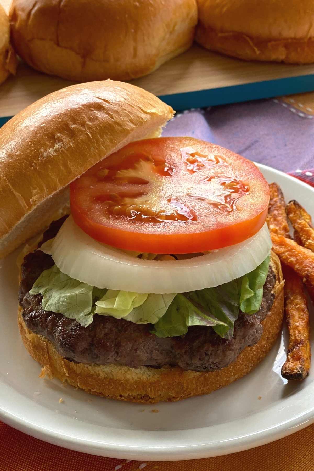 American Wagyu burger on a brioche bun topped with lettuce, onion and tomato.