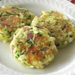 3 zucchini cakes on a plate.