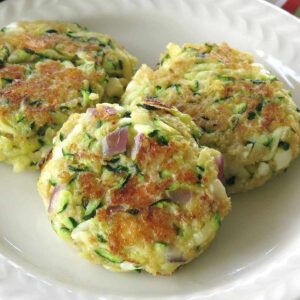 3 zucchini cakes on a plate.