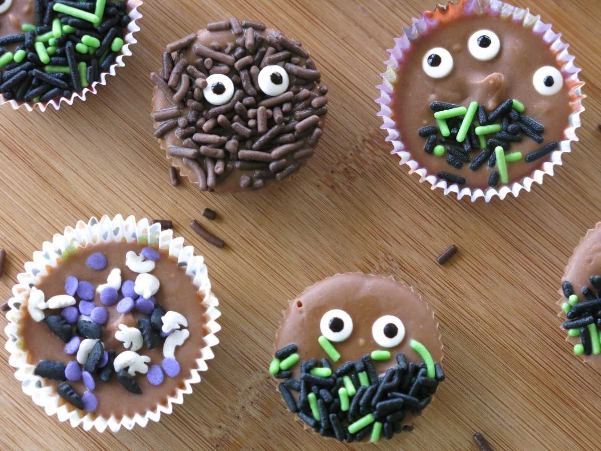 Serving board with cups of chocolate Halloween fudge decorated like monsters.