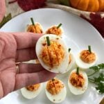 Hand holding a pumpkin deviled egg.