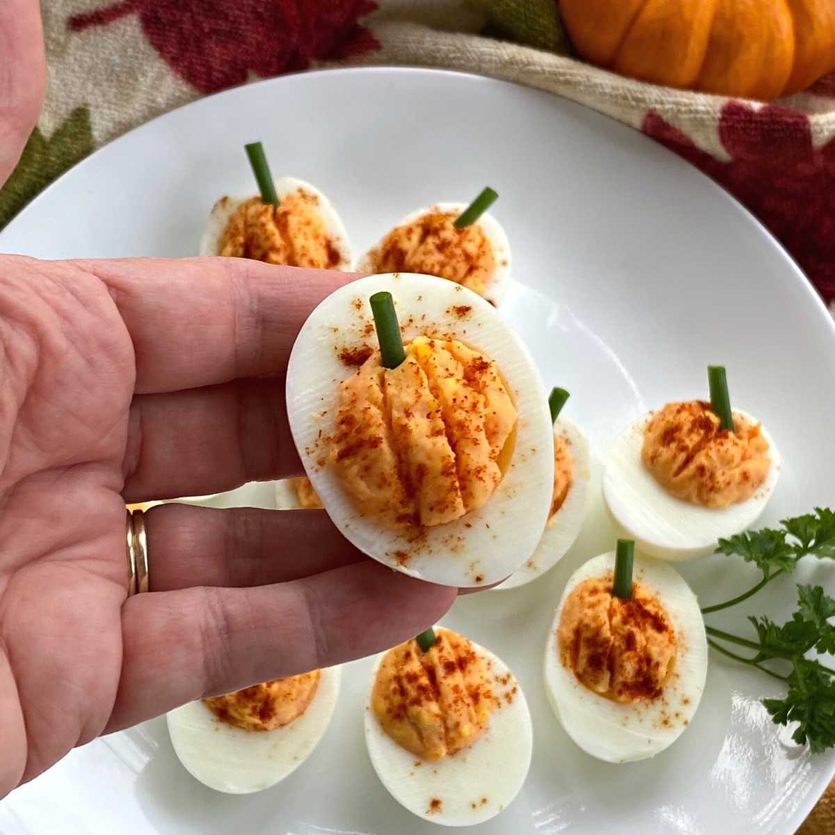 Hand holding a pumpkin deviled egg.