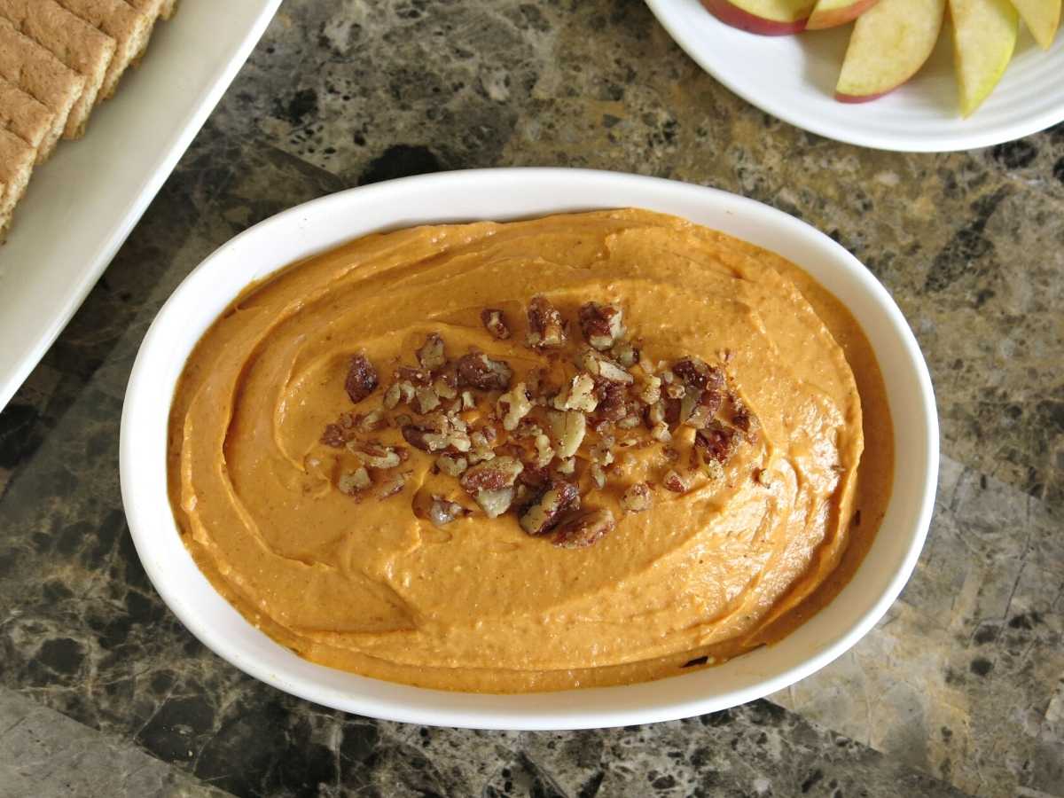 Large serving dish with pumpkin cheesecake dip topped with candied pecans.