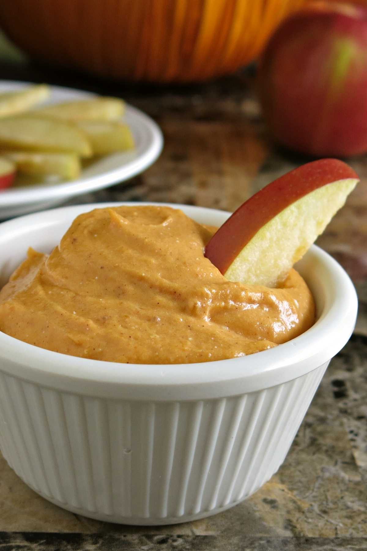 Pumpkin Cream Cheese Dip in serving cup with apple wedge.