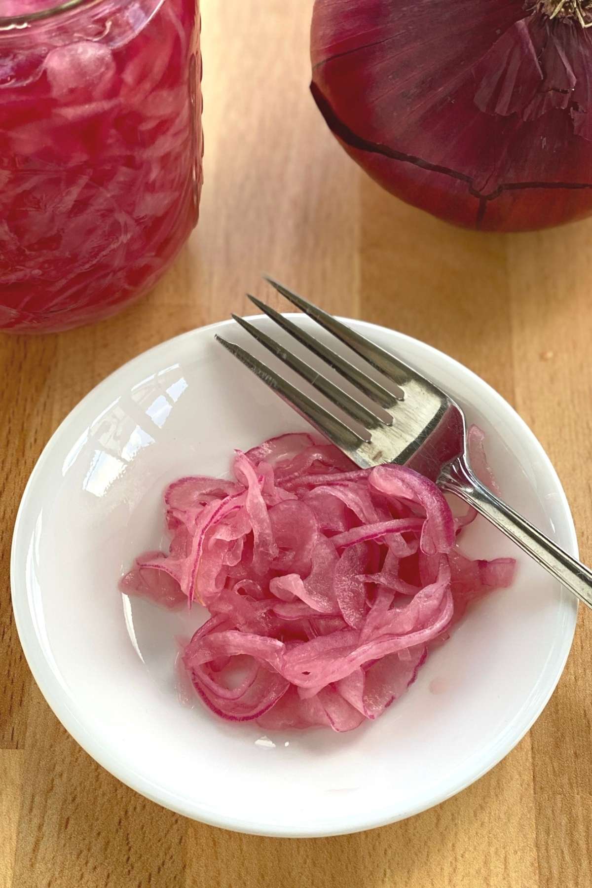 Pickled pink onions on plate with a fork.