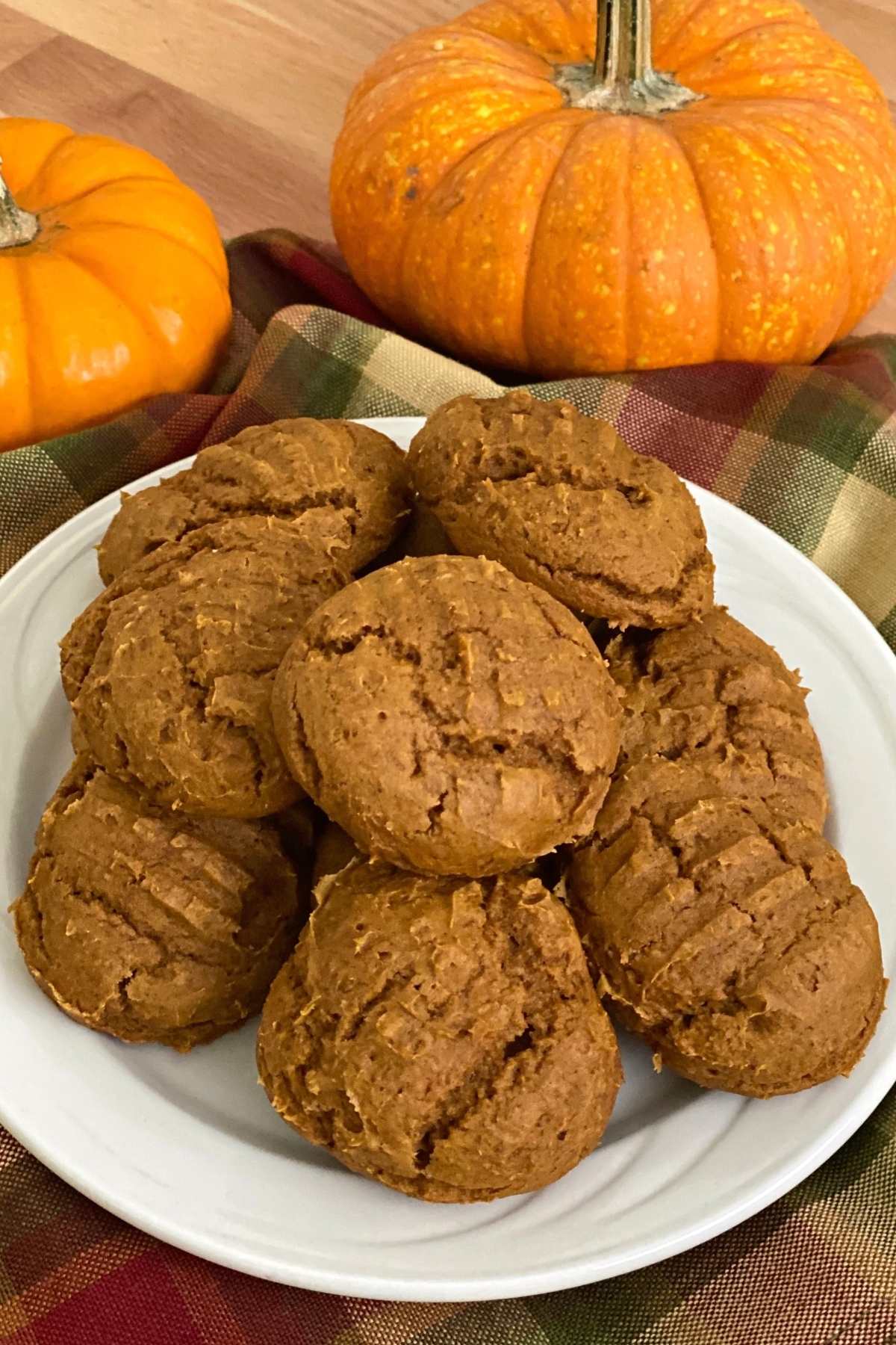 Plate of 2-ingredient pumpkin cookies made with cake mix with 2 pumpkins behind them.