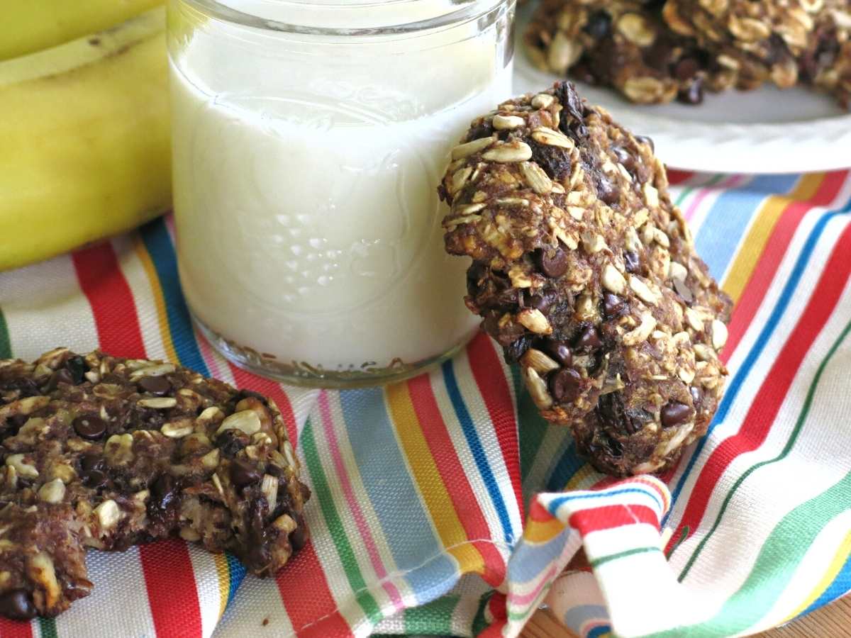 Vegan banana everything cookie leaning against a glass of milk.