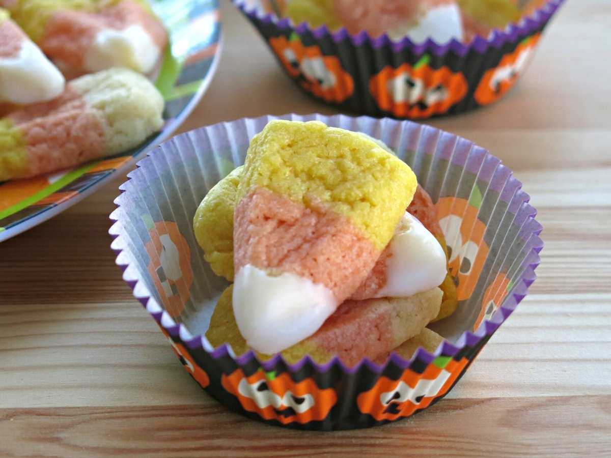 Tiny candy corn sugar cookies in a paper cup.