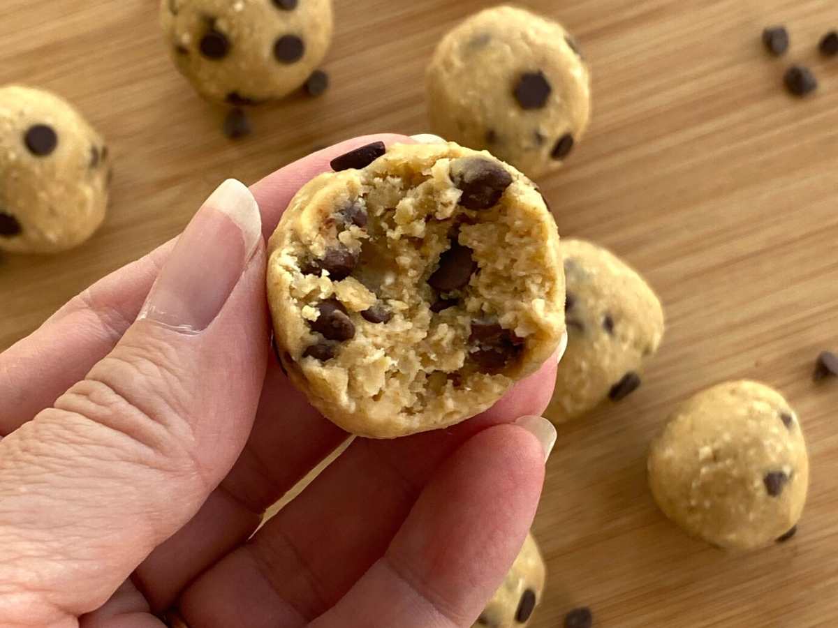 Hand holding a chickpea cookie dough balls with a bite removed.