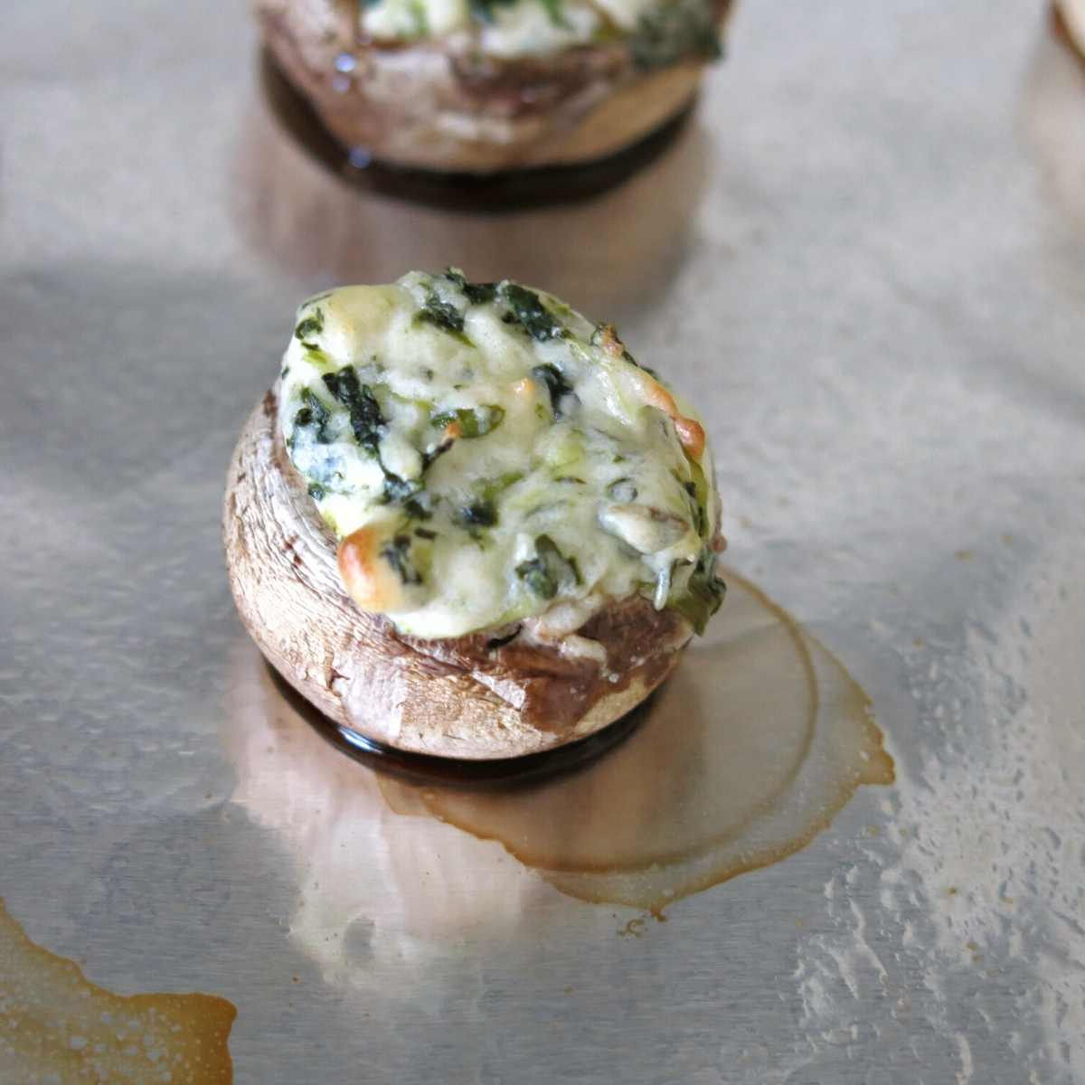 Juices pooling at the bottom of a cooked stuffed mushroom.