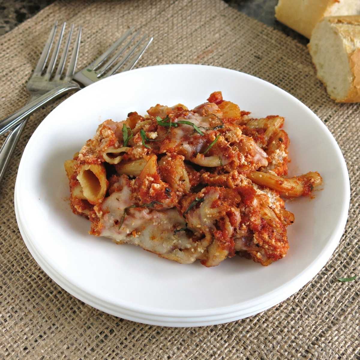 Serving of crock-pot ziti on a plate with bread on the side.