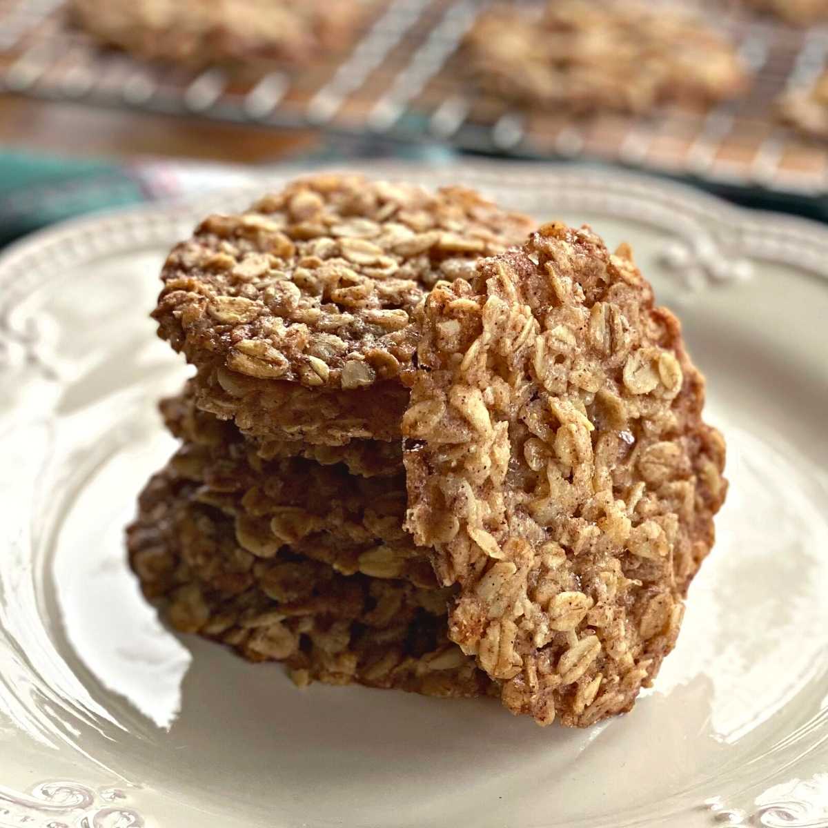 Oatmeal lace cookies in a stack with one leaned against the stack.