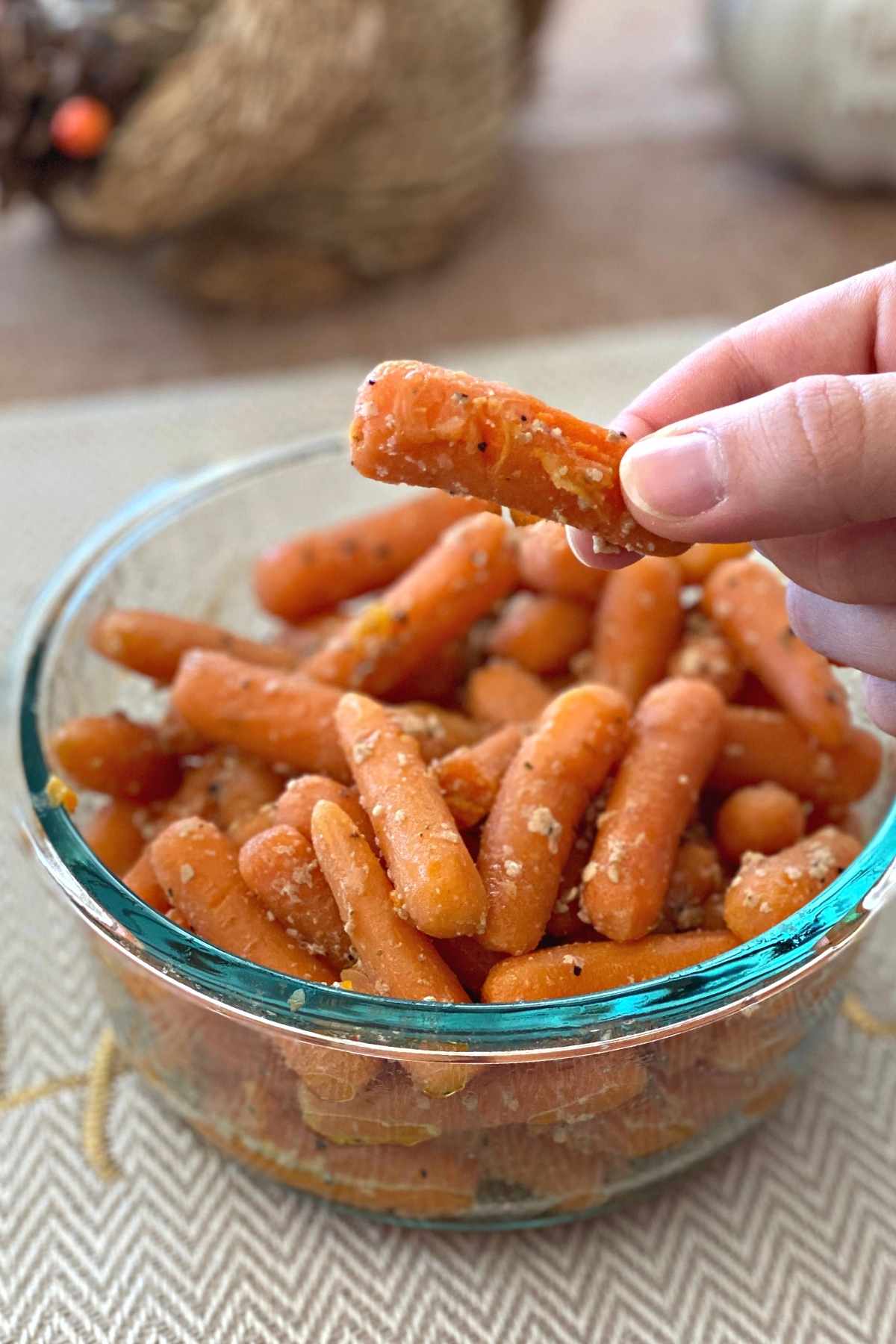 Fingers holding a sauteed baby carrot.