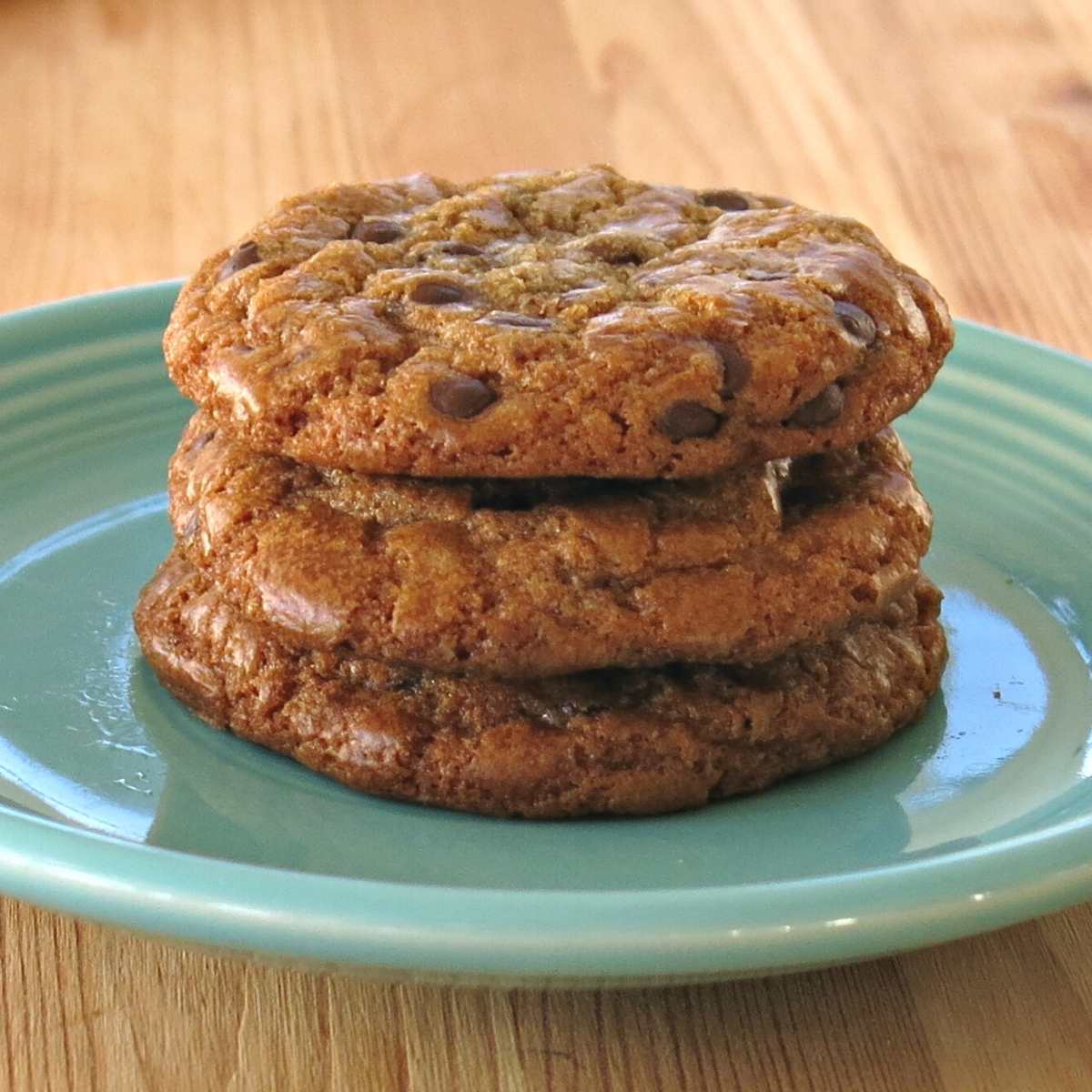 3 chocolate chip cookies made with brown butter stacked on a plate.