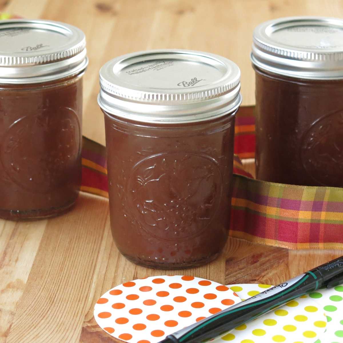 Three mason jars with sugar-free apple butter in them surrounded by gift tags and ribbon.
