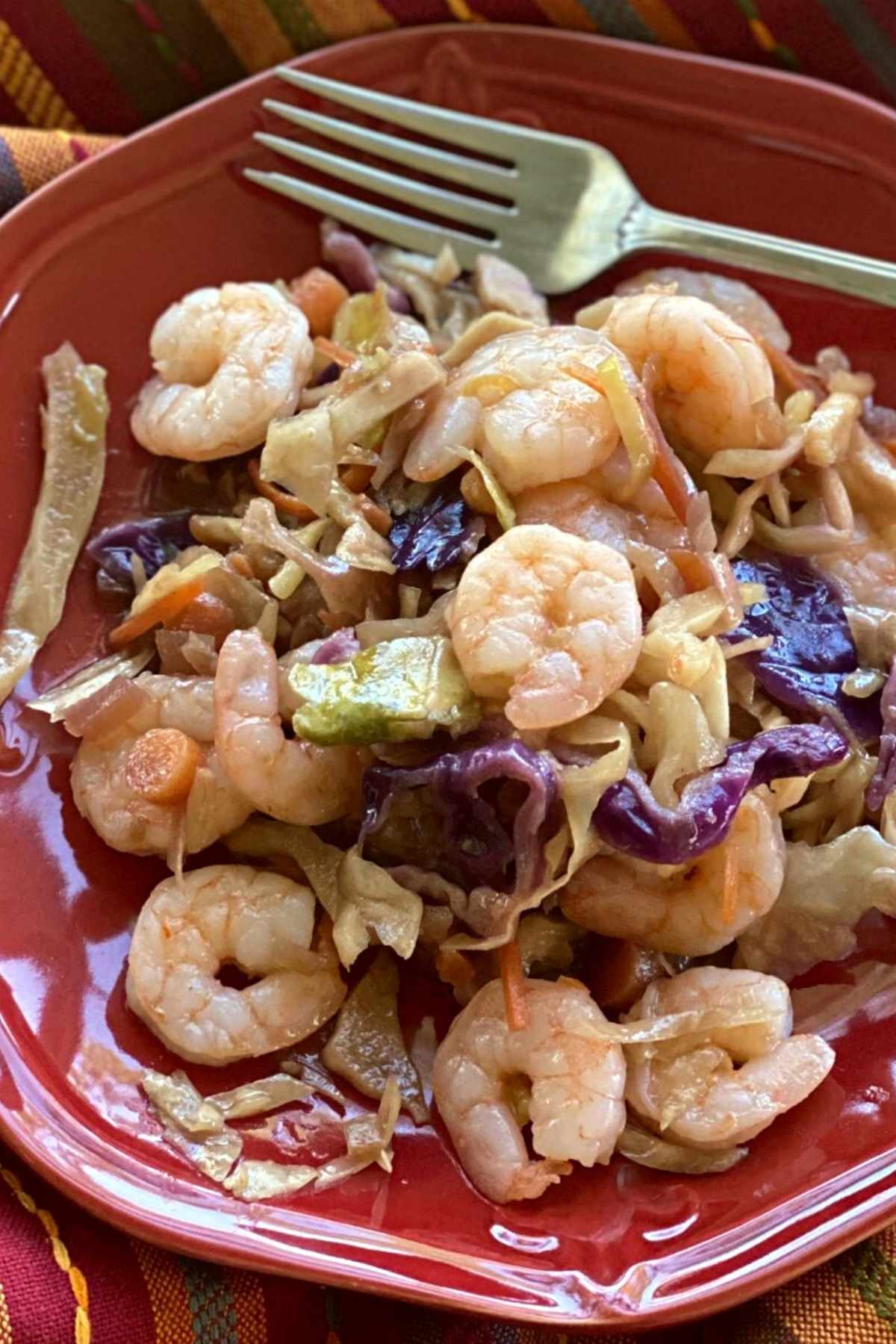 Shrimp egg roll in a bowl on a red plate with a fork.