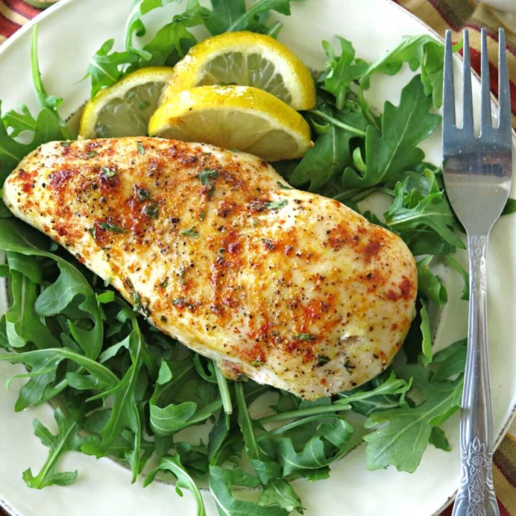 Baked lemon pepper chicken on a plate with a fork.