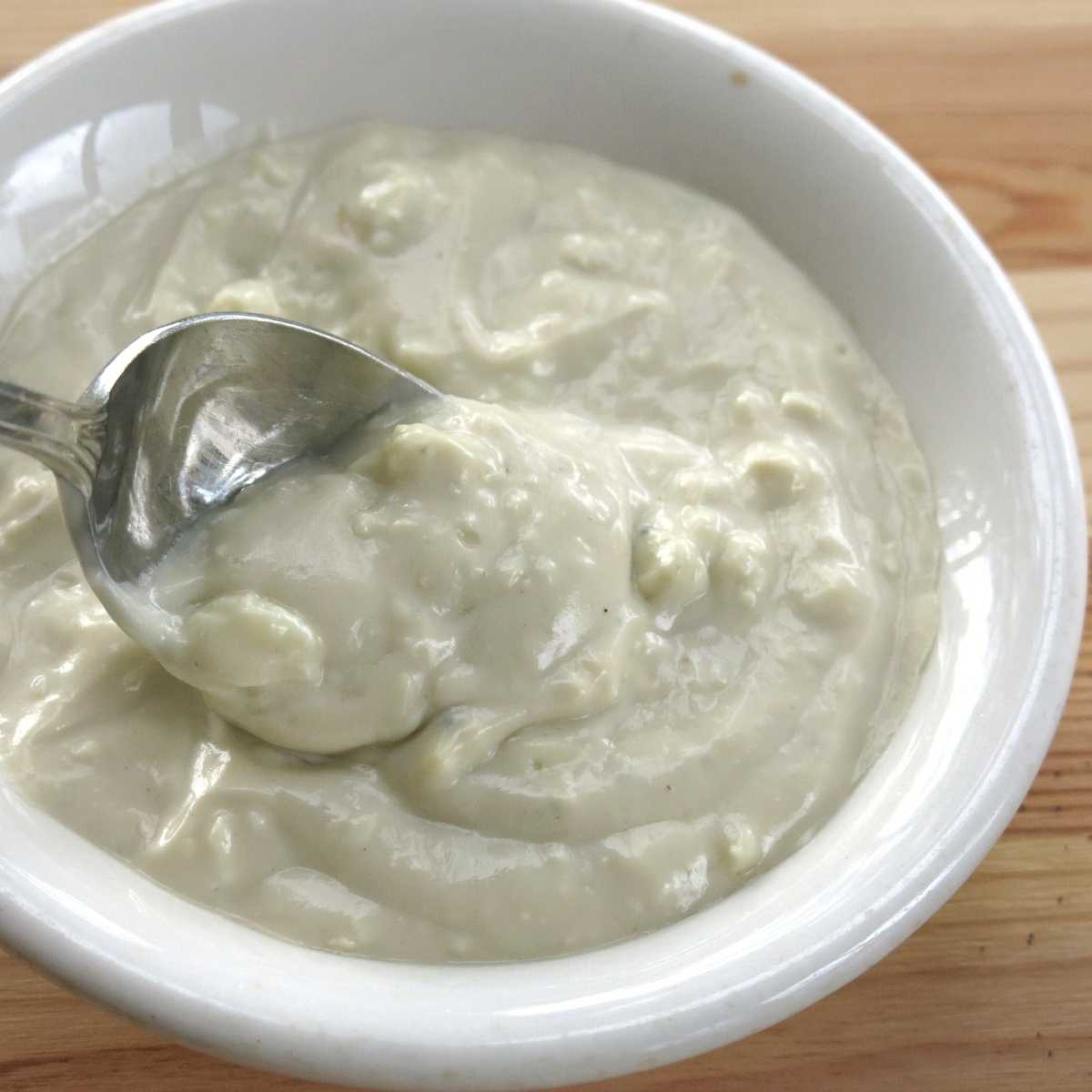 Easy blue cheese sauce in a bowl with a spoon lifting some out.