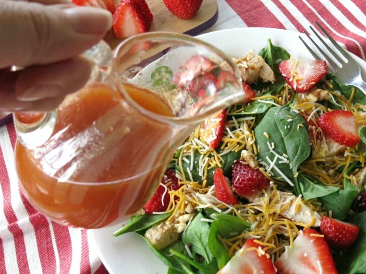 Sweet red wine vinegar dressing being poured over a green salad.