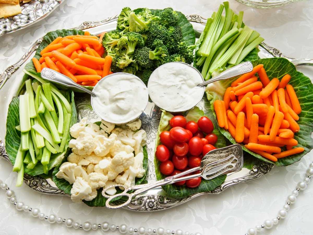 Platter of assorted cut vegetables around cups of dip.