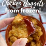 Fingers holding a chicken nugget cooked from frozen in an air fryer.