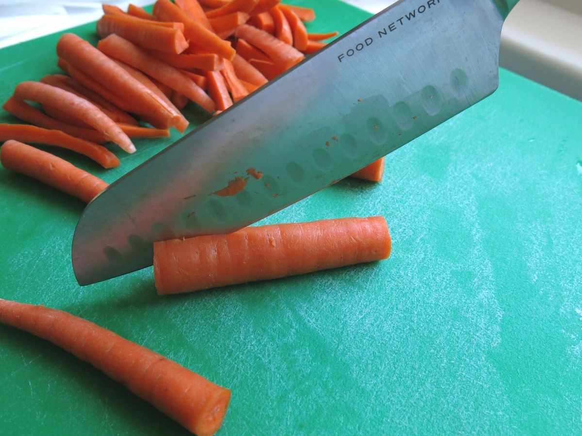 Carrots being cut into the shape of french fries.