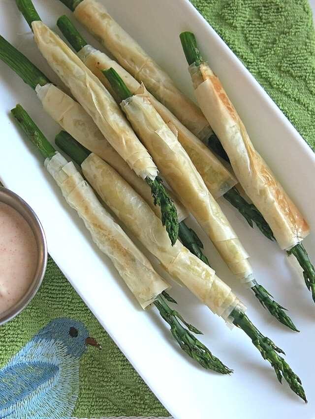 Phyllo wrapped asparagus on a platter next to aioli.