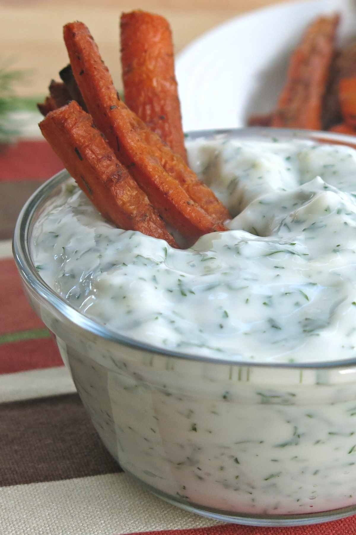Several carrot fries standing upright in a  small bowl of yogurt dip.