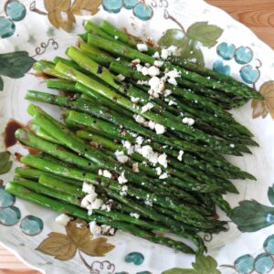 Roasted asparagus with balsamic glaze and feta cheese on a platter.