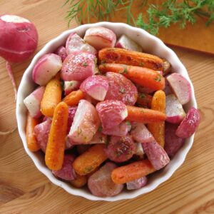 Roasted radishes and carrots in a lemon butter dill sauce in a serving bowl.