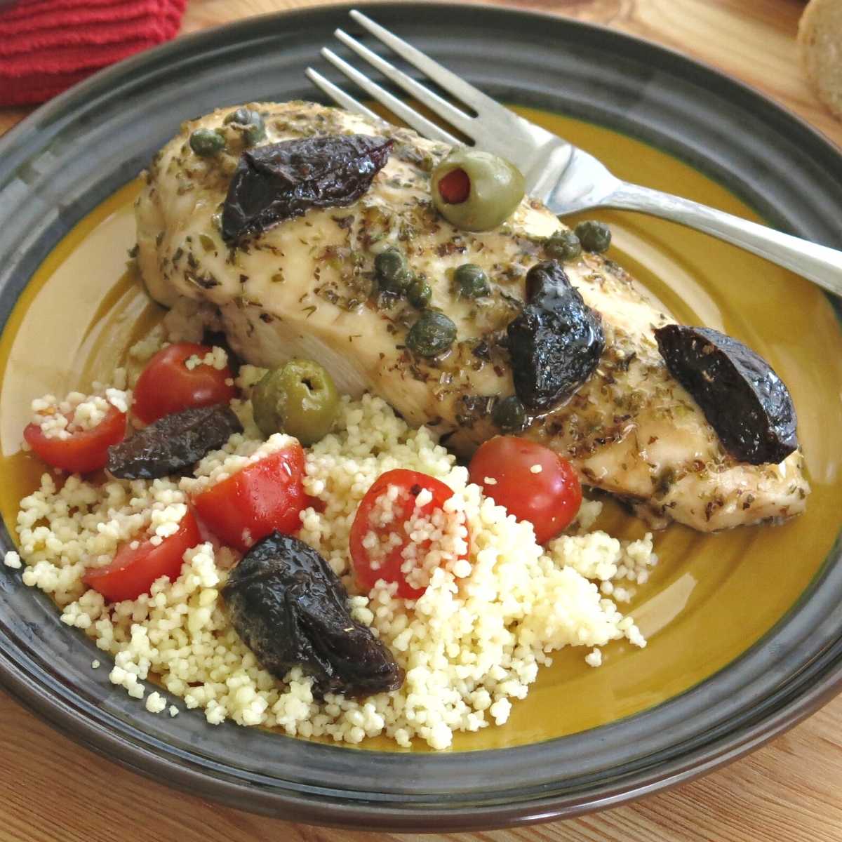 Chicken Marbella on a plate with couscous.