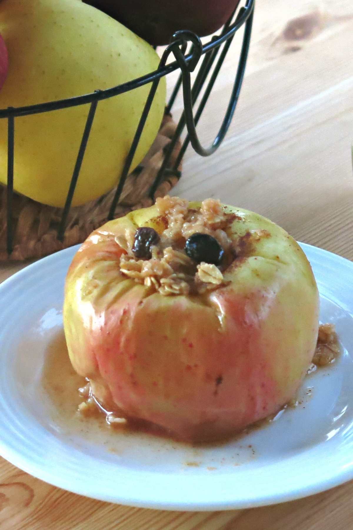 Whole apple baked in the microwave on a plate with juices on the plate. 