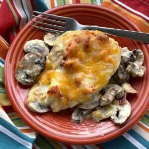 Alice Springs Chicken topped with honey mustard and cheese on plate with mushrooms surrounding it.